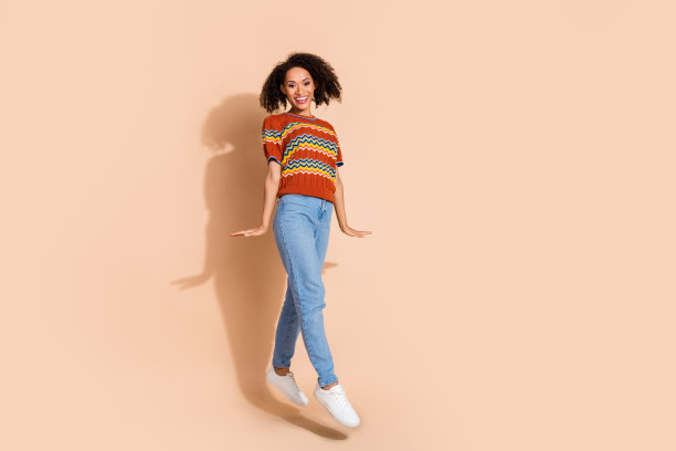 全尺寸照片华丽可爱乐观的女人穿针织t恤牛仔裤飞像娃娃孤立在米色背景图片下载