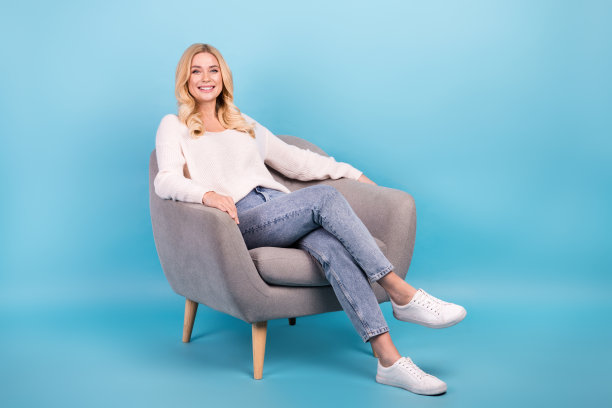 照片中的开朗可爱的女人穿着时尚的白色衣服，先生的椅子孤立在蓝色的背景图片下载