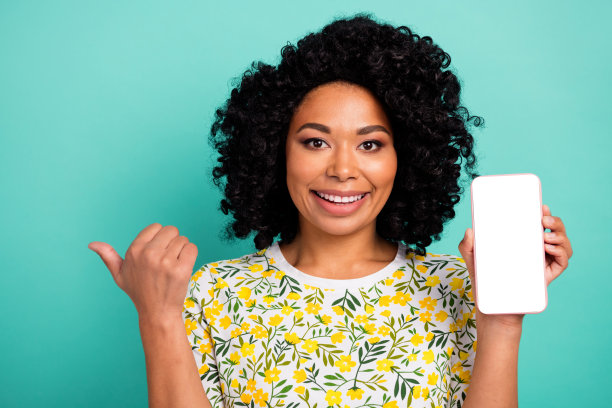漂亮的年轻女子的照片空空间手机显示点手指空空间穿t恤孤立在蓝绿色的背景图片下载