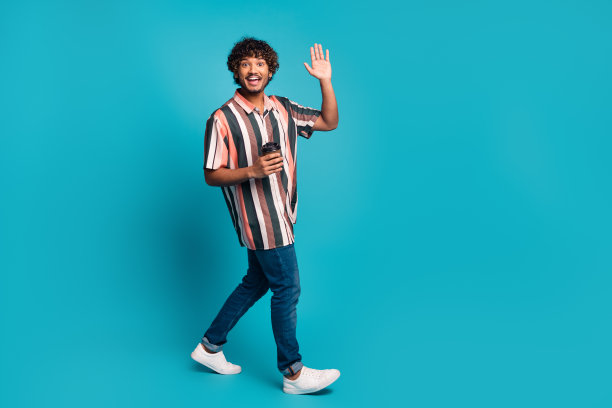 开朗积极的家伙全身照片穿着条纹衬衫喝饮料挥舞手臂他空旷的空间孤立的蓝色背景图片下载