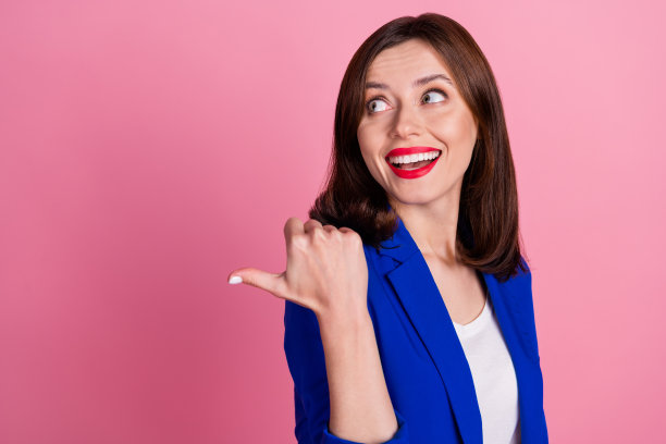 年轻兴奋的女商人穿着蓝色正装的肖像照片手指指向空白好奇的最好提供孤立在粉红色的背景图片下载