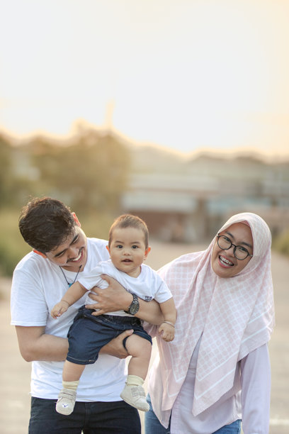快乐的婴儿男孩，父母在镜头前大声笑着。一个非常幸福和愉快的年轻家庭。下午的户外照片。图片下载