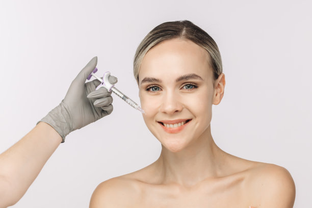 一位女性自信地在白色背景前摆姿势，旁边放着一支注射器。这张图片捕捉了美容服务的本质，突显了自我护理和皮肤健康的重要性。图片下载