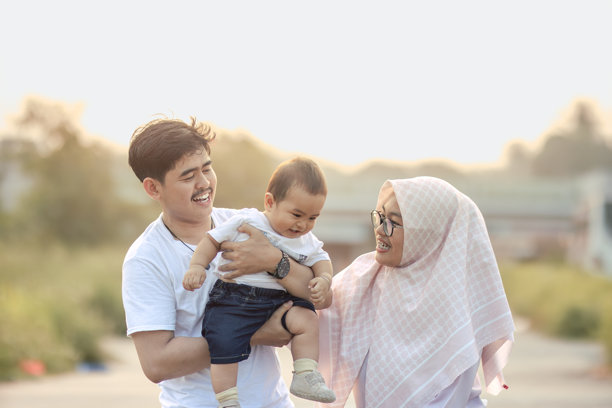 快乐的婴儿男孩，父母在镜头前大声笑着。一个非常幸福和愉快的年轻家庭。下午的户外照片。图片下载