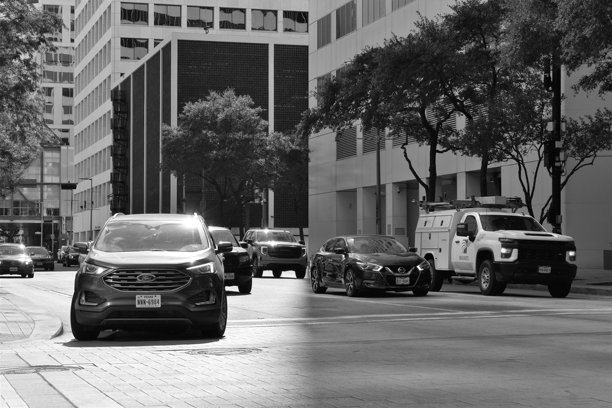 一辆本田CR-V在城市金融区的繁忙高峰交通中领先一群竞争者。这张照片被转换为黑白色调，以营造怀旧而独特的效果。图片下载