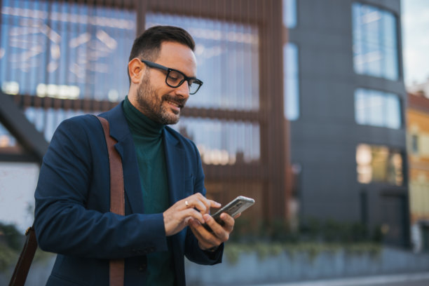 一位英俊、微笑、穿着得体的中年男士正前往工作，手中拿着公文包，背景是一座现代建筑。这张照片捕捉了快节奏的生活方式和商业时刻。图片下载