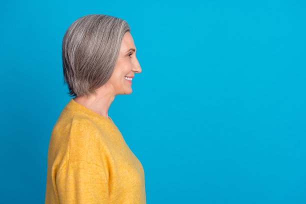 成熟迷人的女士肖像照片，微笑，穿着时尚的黄色服装，背景为蓝色，适合广告横幅使用。图片下载