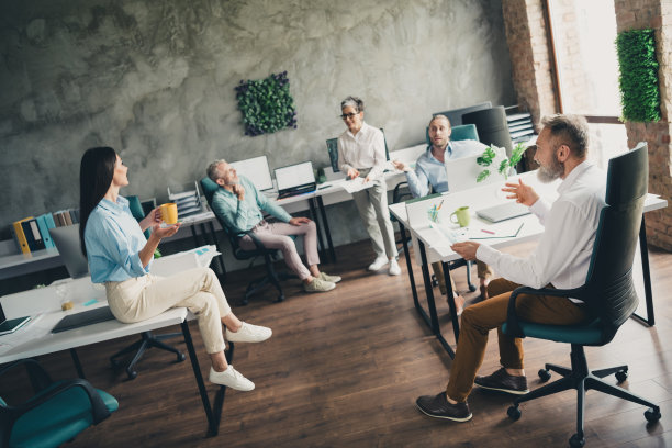 团队成员在现代办公室阁楼内舒适的工作空间中一起工作，享受咖啡休息时间，聊天交流的全身照片图片下载