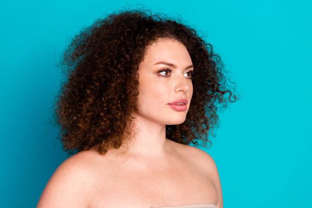 漂亮年轻女性的头像照片，光滑的肩膀，背景为青绿色，空白空间。图片下载