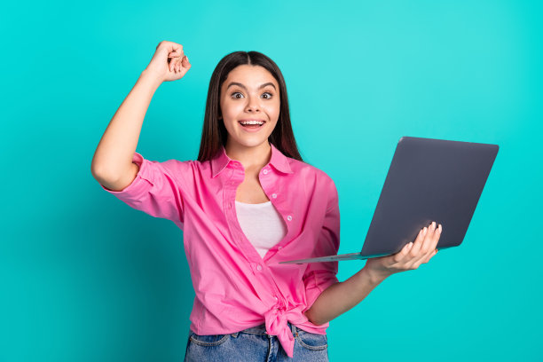 手持上网本的时尚粉衣少女获胜照片，蓝青色背景图片下载