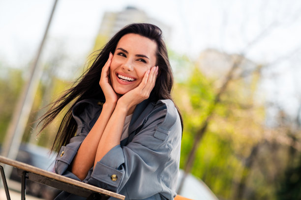 穿着灰色外套，坐在咖啡馆享受户外好天气的迷人女士照片图片下载