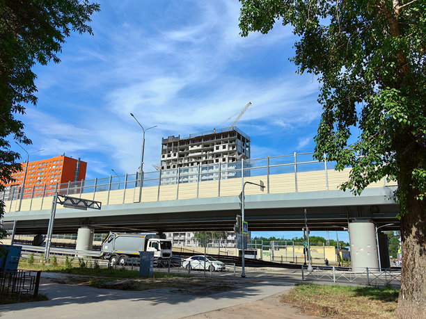 铁路轨道上的桥。桥旁正在建设高层建筑，汽车穿行而过，树木茁壮成长。俄罗斯。夏季。下诺夫哥罗德。齐奥尔科夫斯基街。2024年7月。照片。图片下载