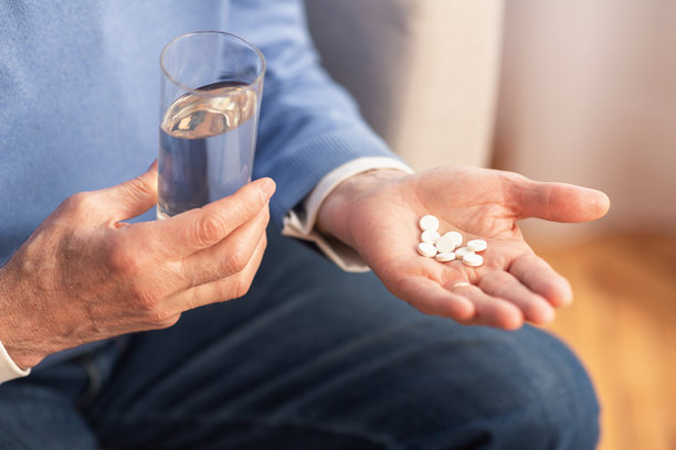 无法辨认的绅士在家中沙发上坐着，手中拿着药丸，裁剪过的图片图片下载