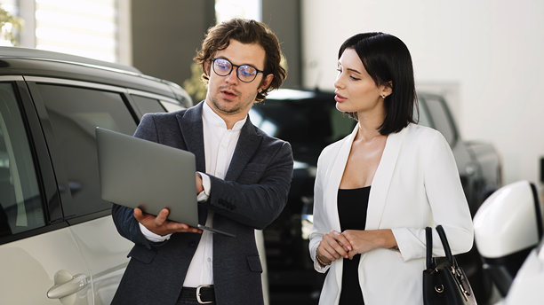 在现代汽车经销商处，顾客在购买前仔细检查一辆流线型汽车。这张照片传达了舒适与科技的氛围，吸引了当今的汽车爱好者。图片下载