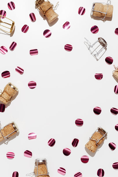 香槟瓶塞和闪亮的紫色彩纸屑，俯视构图，节日庆祝照片。木塞和金属箍在柔和的背景下，阳光投下阴影。平铺的节日简约图案。图片下载