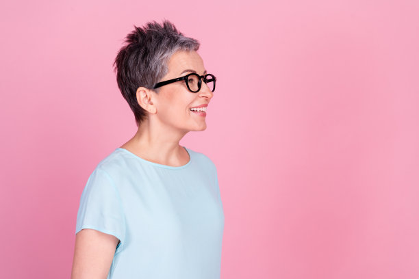 穿着蓝色T恤的和蔼老年女性在粉色背景前凝视空旷的空间的个人头像照片图片下载