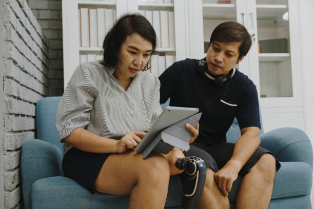 一对情侣和她的腿部残疾女友在假期中放松，享受在iPad上玩耍和在线听音乐的乐趣。图片下载