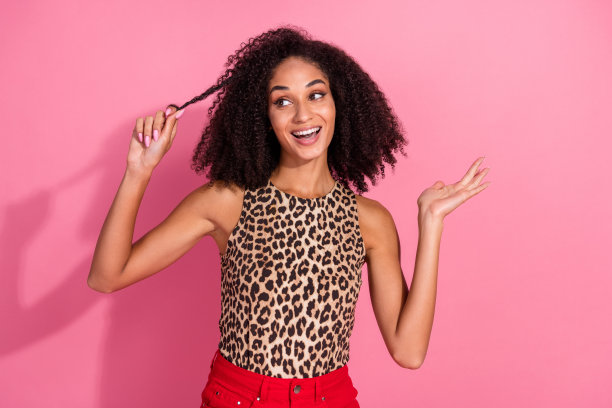 可爱年轻女性的照片肖像，穿着时尚的豹纹服装，头发使用护发素，背景为粉色。图片下载