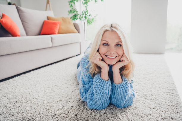 美丽的老年女性在现代公寓室内的地板上休闲躺着的全身照片图片下载