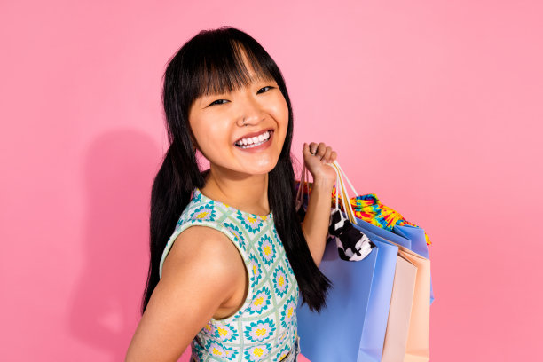 俯视图照片，漂亮的女孩顾客穿着时尚衣服，手持购物袋，置身于粉色背景的商场促销中。图片下载