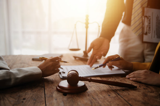 律师和商业人士在办公室讨论合同文件，桌上有一个铜制天平。法律、法律服务、咨询、正义和法律概念的图片，带有胶卷颗粒效果。图片下载