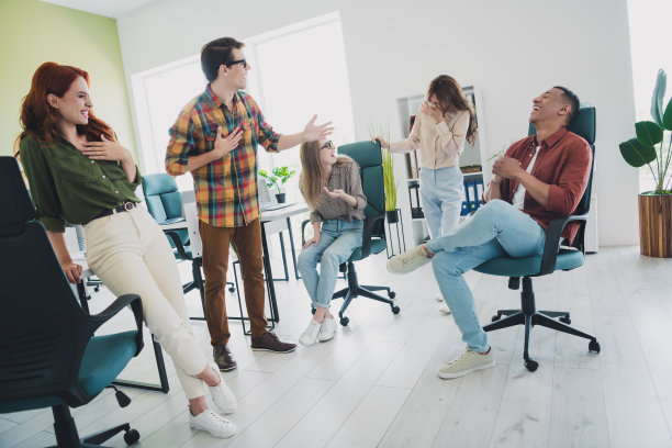 五名年轻的企业员工在办公室商务中心的工作站内聊天和开玩笑的照片图片下载