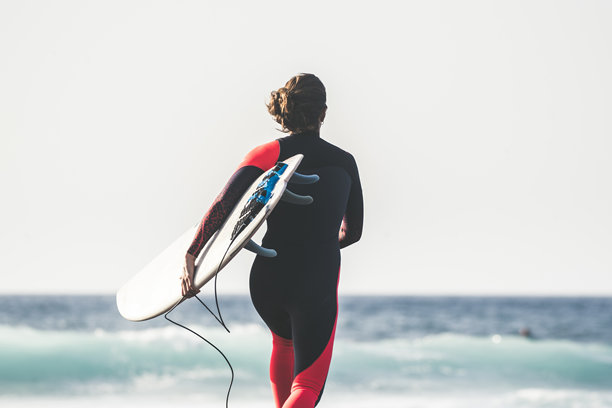 少女与冲浪板在海滩上对天空奔跑的后视图图片下载