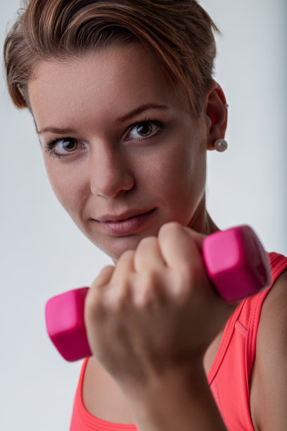 年轻女人特写照片中举着粉色哑铃图片下载