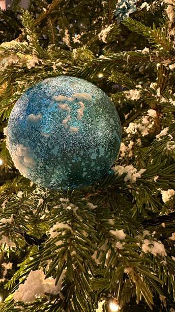 城市夜晚的圣诞树上闪烁着明亮的灯光、花环和装饰，手机拍摄的照片图片下载