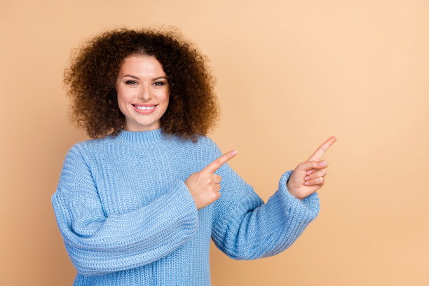 年轻女销售员的肖像，卷发，手指指向空白处，展示最佳优惠价格，背景为米色。图片下载