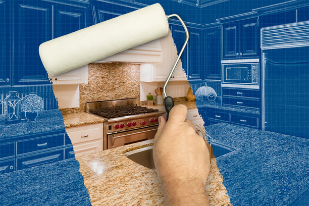 男人用滚筒涂料在蓝图草图下揭示定制厨房的前后对比照片。图片下载