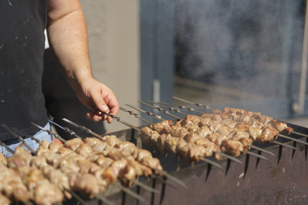 美丽的照片展示了多汁的烤肉串在冒烟的烤架上烤制。街头美食概念图片下载