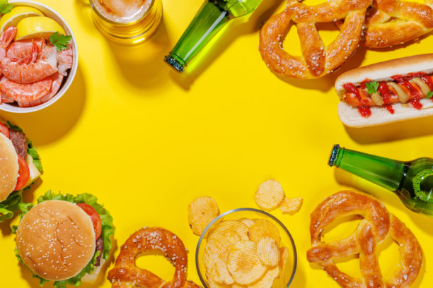 一张生动的照片，展示了一杯啤酒，周围是各种小吃和快餐。图片下载