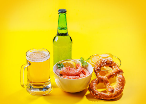 一张生动的照片，展示了一杯啤酒，周围是各种小吃和快餐。图片下载