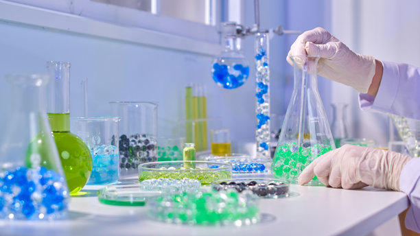 实验概念的宣传照片，一位科学家坐在窗边的桌子上，正在用五彩的水凝胶球进行实验。侧面视图，留有添加文本的空间。图片下载