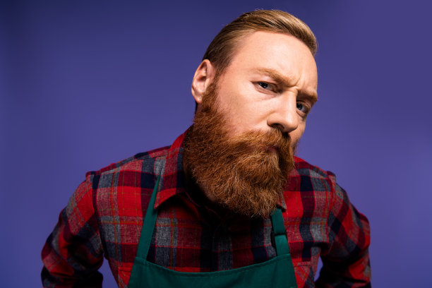 穿着红色格子衬衫和绿色围裙的帅气男士在紫色背景下听新闻的照片图片下载