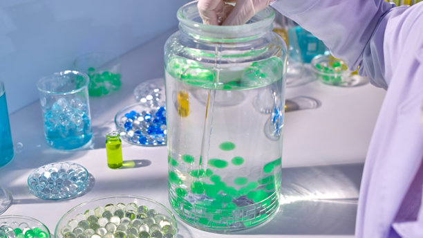 高角度拍摄的白色实验室桌面照片，展示了一个装有水和水球的大玻璃花瓶。创意设计模板，留有空白文本空间。图片下载