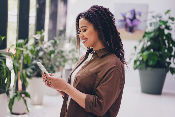 成功年轻女商人的个人照片，穿着衬衫，在现代商务中心办公室内使用智能手机。图片下载