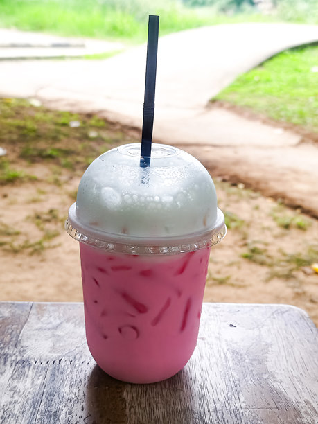 泰式粉红牛奶垂直照片，摆放在自然环境中的餐桌上，清迈，泰国。图片下载