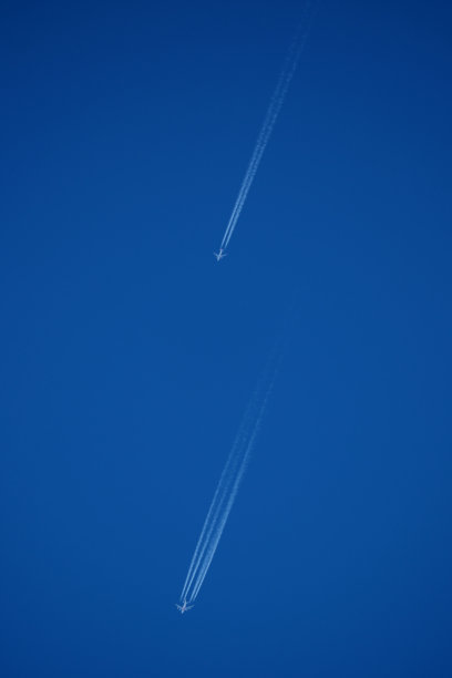 两架飞机在蓝天中留下的航迹，照片特写。蓝天中的飞机尾迹。图片下载