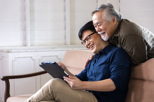退休年龄的亚洲老年男性正在查看儿子平板电脑上可在线购买的产品照片，旁边留有空白空间。图片下载