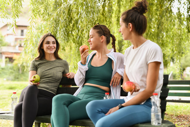 两位女性专心倾听第三位朋友的故事，同时享用苹果，为晨跑充电。图片下载