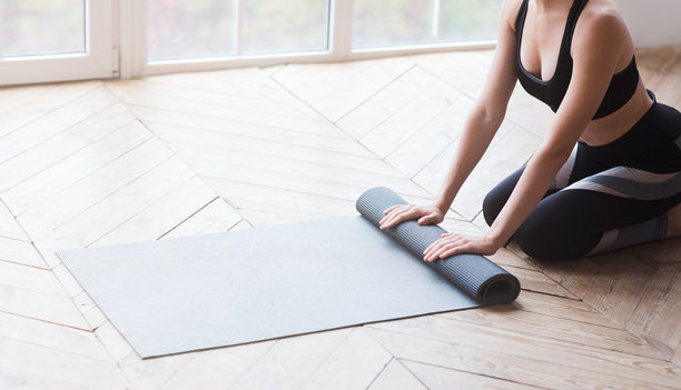 瘦女人正在卷运动垫的裁剪照片图片下载