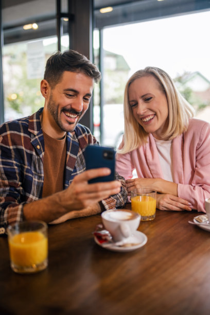 一群朋友在咖啡馆相聚，正在手机上查看照片，享受快乐的时光。图片下载