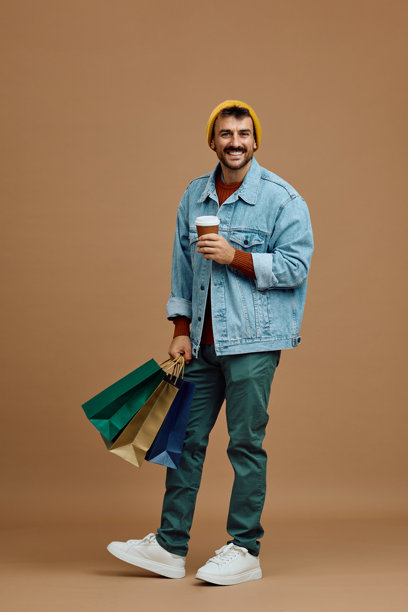 快乐的男人手拿购物袋和外卖咖啡，面向镜头拍摄的工作室照片。图片下载
