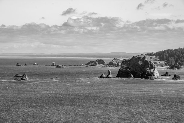 一幅黑白照片，展示了从悬崖顶部俯瞰俄勒冈州班登海滩的景色。图片下载