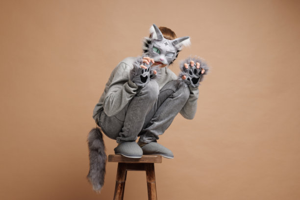 四足健身肖像，穿着猫面具的青少年在米色背景下，摄影棚照片。图片下载