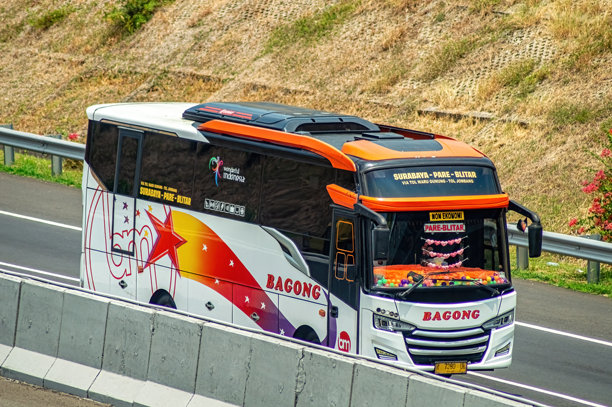 一辆新的城际巴士在收费公路上行驶，展现出鲜艳的色彩和清晰的路线信息。这张图片适合用于关于印度尼西亚交通的文章。印度尼西亚，2024年10月31日图片下载