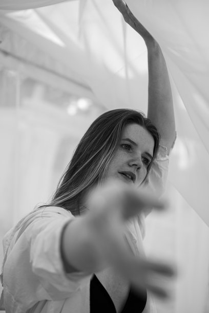 一位迷人的长发女孩在水边的海滩上漫步的肖像。穿着泳衣和衬衫的年轻女性在河边迎接夏日的黎明。黑白照片。图片下载