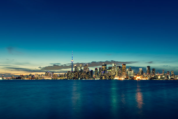 模糊的城市天际线图片，前景有水面图片下载